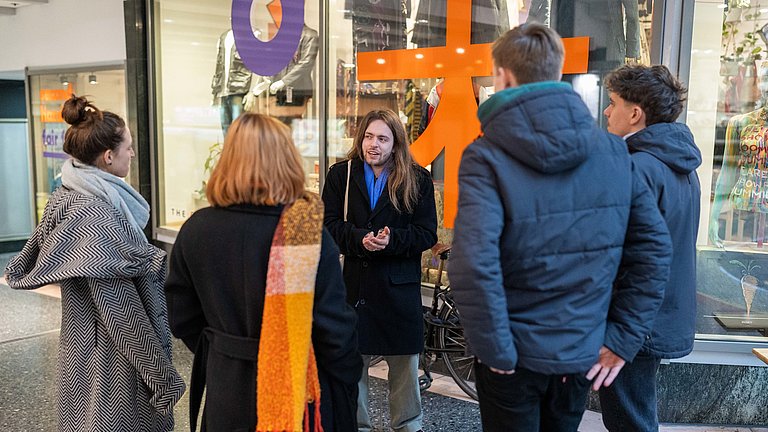 Menschen stehen vor einem Geschäft, eine Person hält eine Ansprache