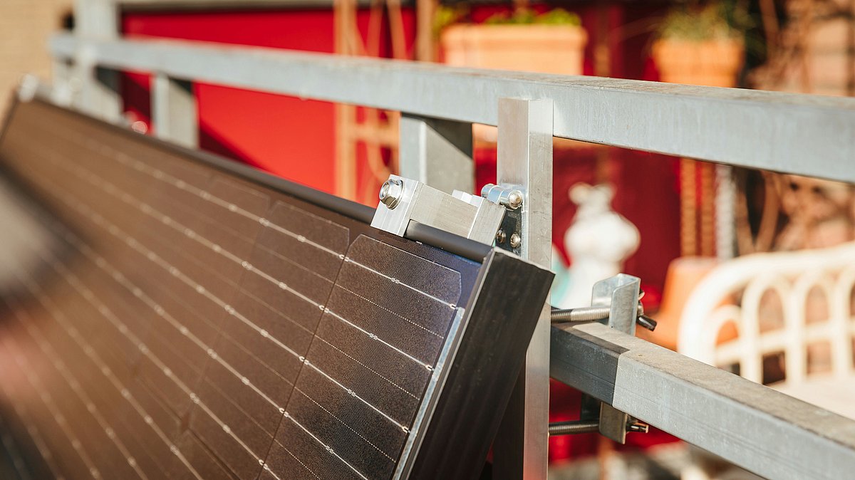 Detailaufnahme eines Solarmoduls, das mit Halterung am Balkongeländer befestigt ist.
