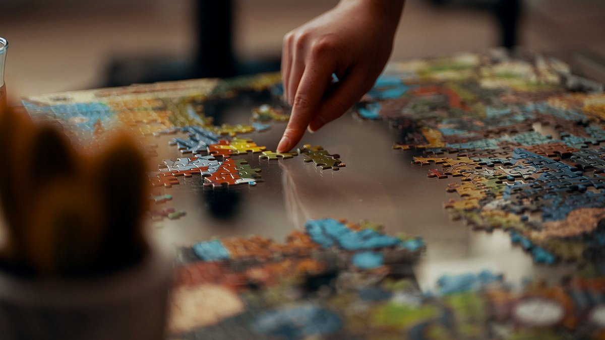 Ein Puzzle wird auf einem Glastisch gepuzzelt