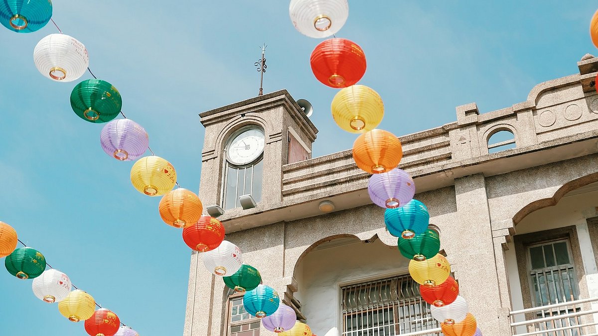 Bunte Lampions hängen in der Luft, im Hintergrund ein Gebäude