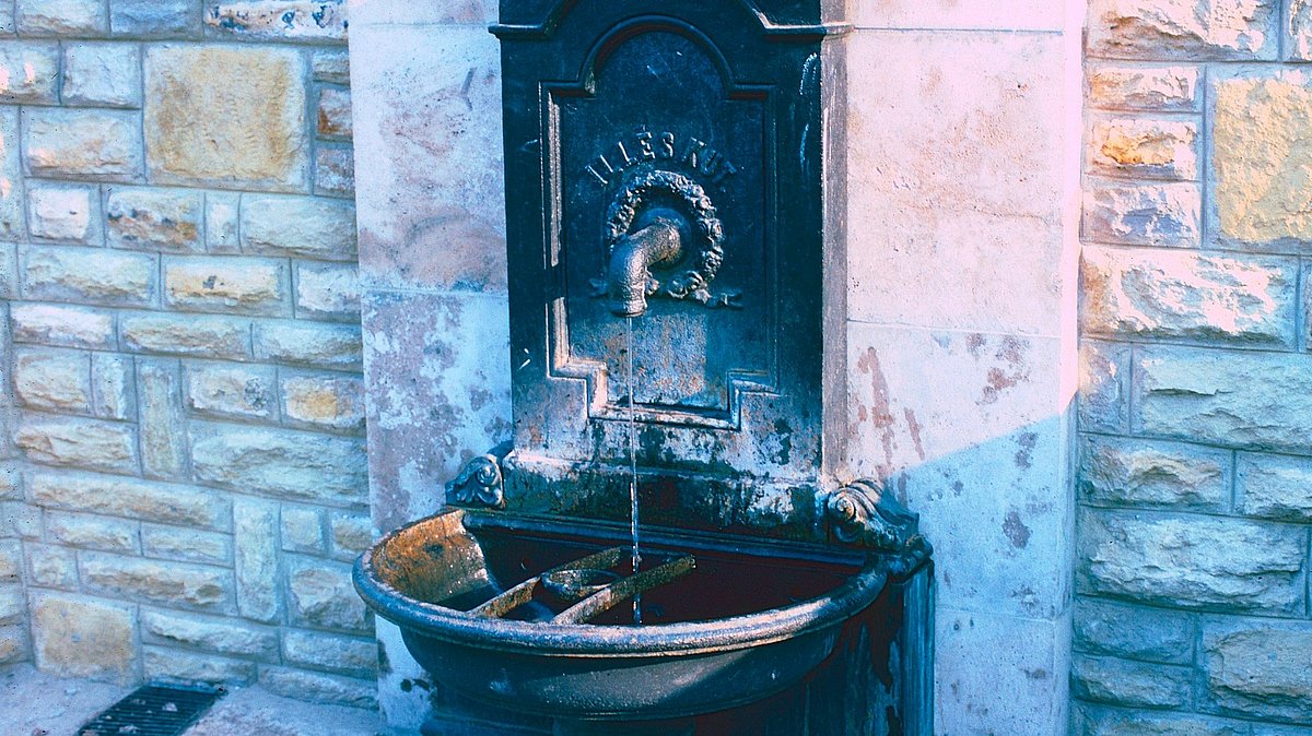 Ein historischer Trinkbrunnen an einer Mauer