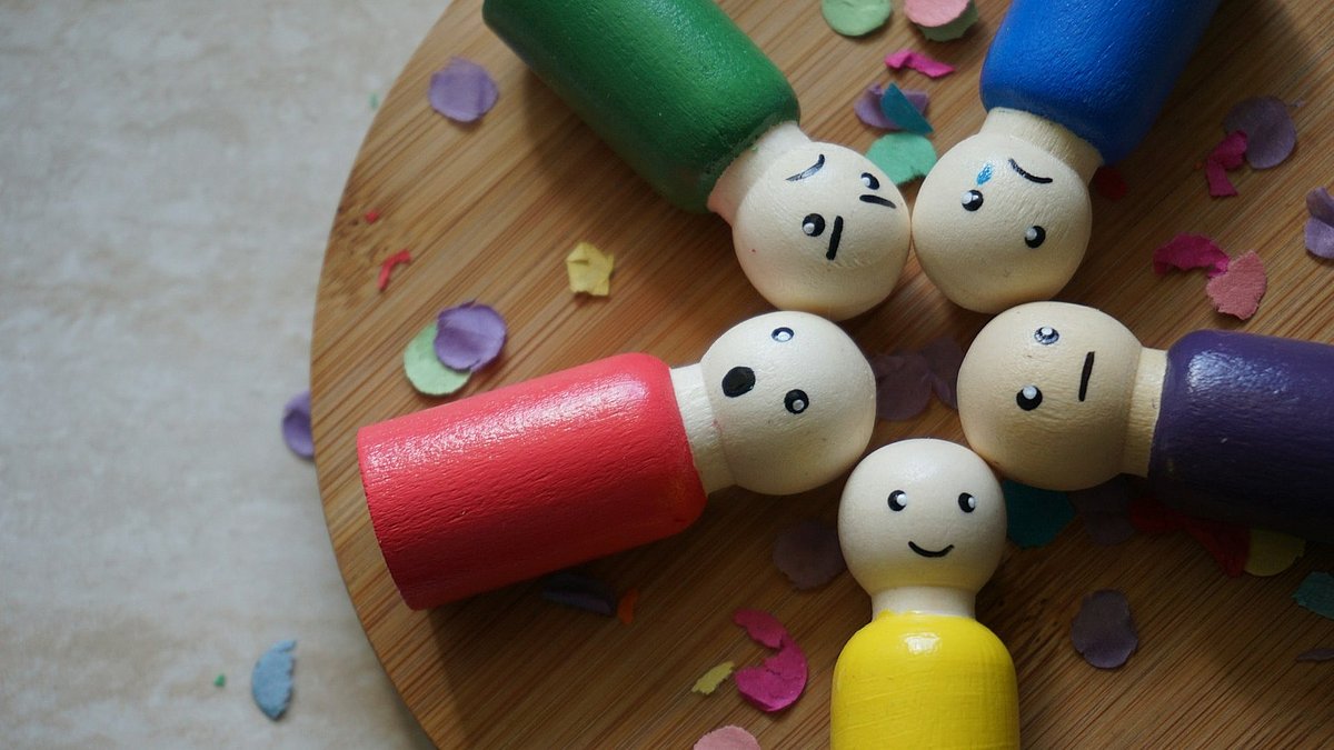 Fünf bunte Spielfiguren liegen nebeneinander und haben unterschiedliche Mimik