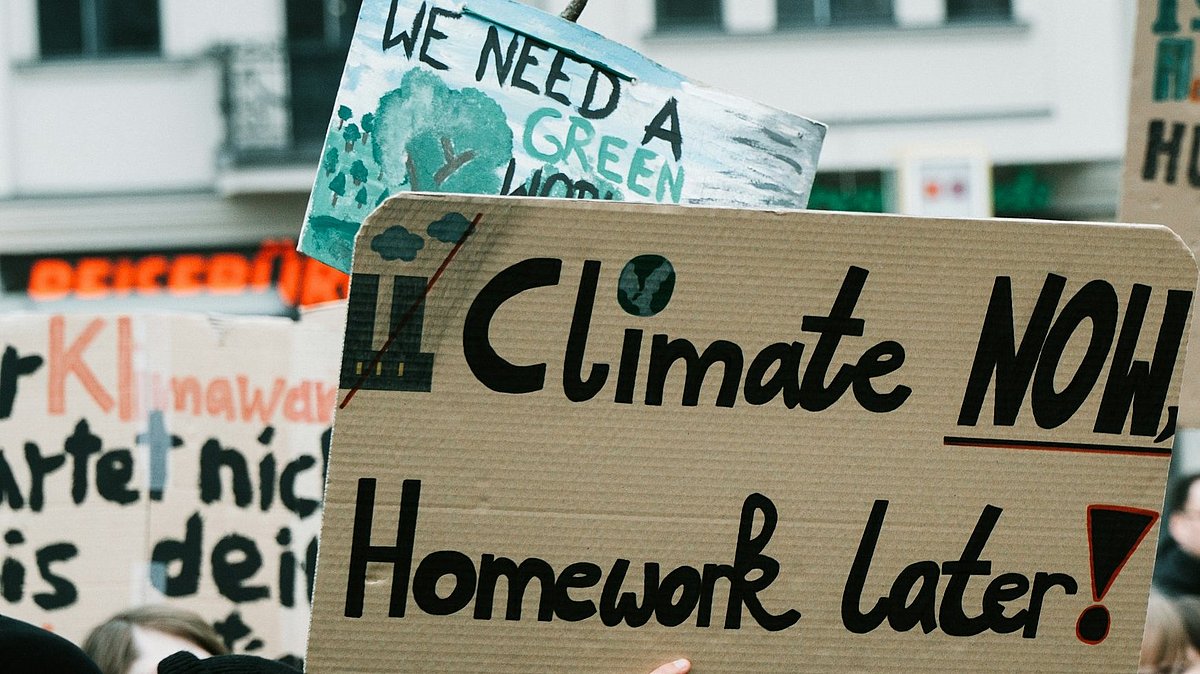 Menschen auf einer Klimademo mit Schild "climate now, homework later"