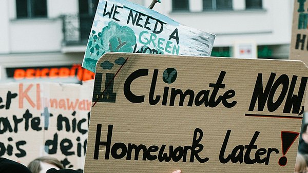 Menschen auf einer Klimademo mit Schild "climate now, homework later"