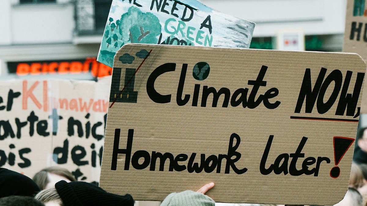 Menschen auf einer Klimademo mit Schild "climate now, homework later"