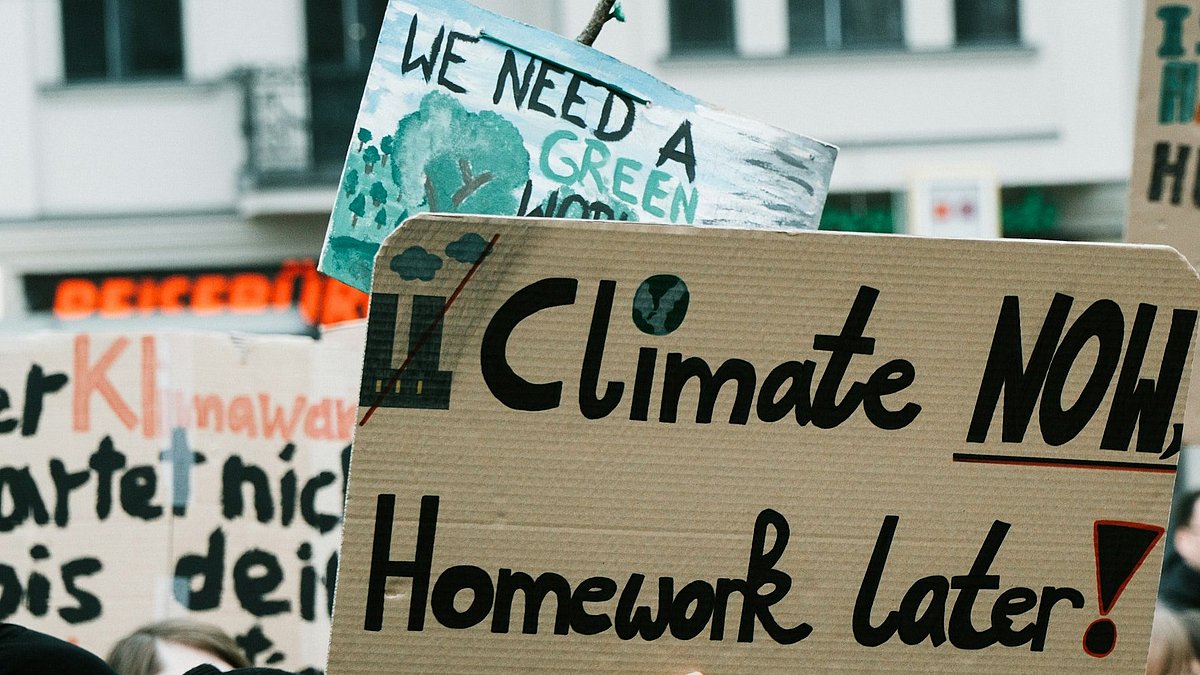 Menschen auf einer Klimademo mit Schild "climate now, homework later"