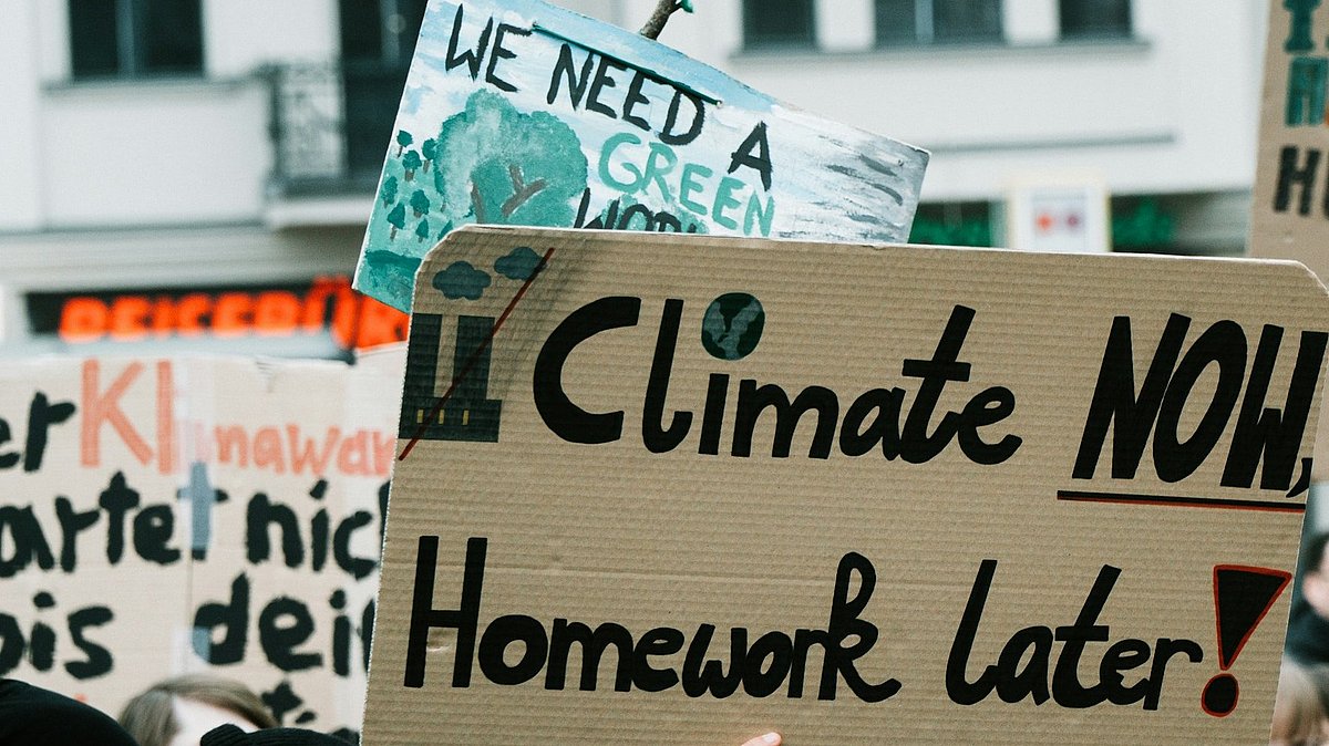 Menschen auf einer Klimademo mit Schild "climate now, homework later"