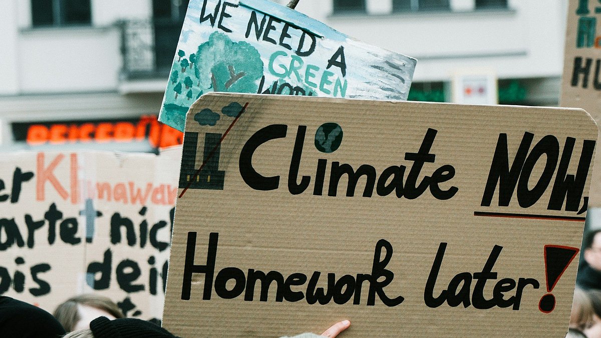 Menschen auf einer Klimademo mit Schild "climate now, homework later"