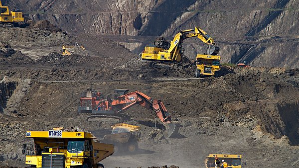 Mehrere Bagger stehen in einem Abbaufeld