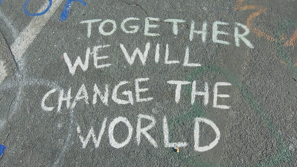 Mit Kreide auf die Straße geschriebener Spruch "Together we will change the world"