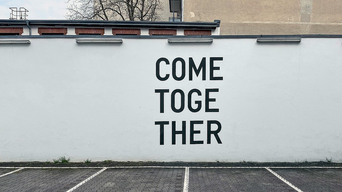 "Come together" Schriftzug auf einer weißen Mauer