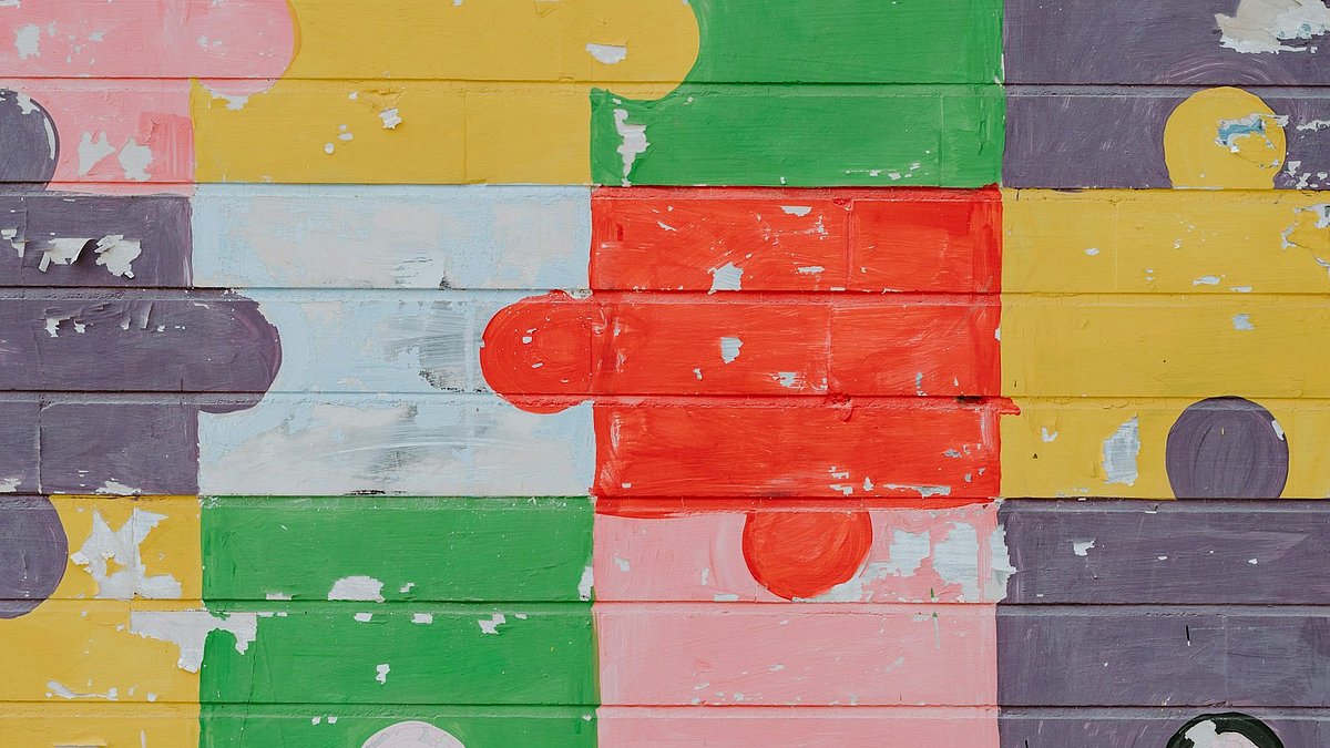 Bunte Puzzleteile sind an eine Wand gemalt