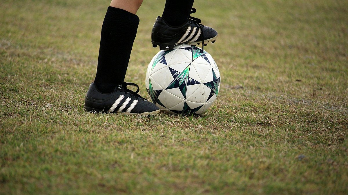 Ein Spieler hat den Fußball zwischen den Beinen