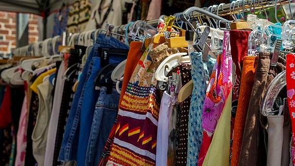 Bunte Auswahl an Kleidungsstücken auf Kleiderstangen bei einem Kleidertausch.