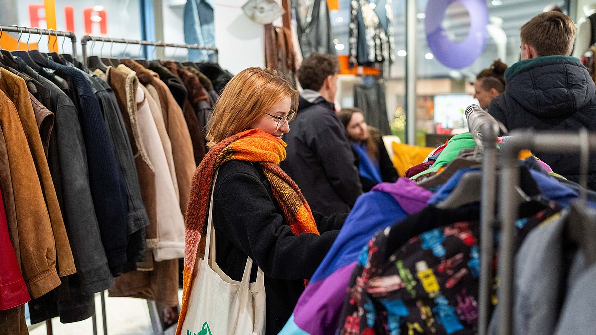 Menschen entdecken gemeinsam Kleidung in einem gemütlichen Secondhandladen.